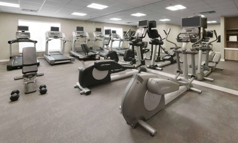 Fitness center at Sonesta ES Suites Fort Worth Fossil Creek, featuring free weights, a mirrored wall, and range of exercise machines.