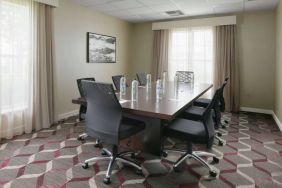 Meeting room in Sonesta ES Suites Fort Worth Fossil Creek, furnished with long wooden table and eight swivel chairs.