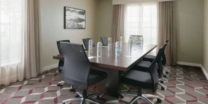 Meeting room in Sonesta ES Suites Fort Worth Fossil Creek, furnished with long wooden table and eight swivel chairs.
