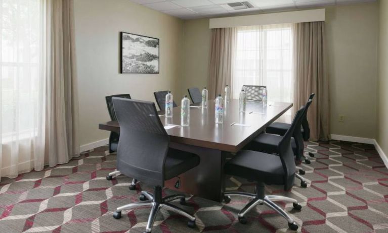 Meeting room in Sonesta ES Suites Fort Worth Fossil Creek, furnished with long wooden table and eight swivel chairs.