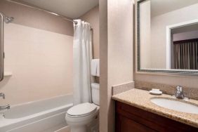 Sonesta ES Suites Tempe guest bathroom, fitted with shower-equipped bath, lavatory, mirror, and sink.