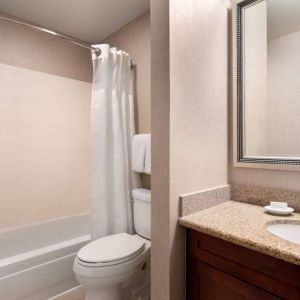 Sonesta ES Suites Tempe guest bathroom, fitted with shower-equipped bath, lavatory, mirror, and sink.