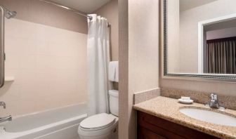 Sonesta ES Suites Tempe guest bathroom, fitted with shower-equipped bath, lavatory, mirror, and sink.