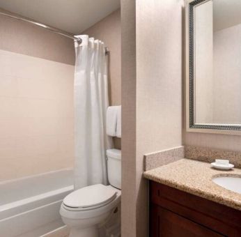 Sonesta ES Suites Tempe guest bathroom, fitted with shower-equipped bath, lavatory, mirror, and sink.