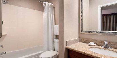 Sonesta ES Suites Tempe guest bathroom, fitted with shower-equipped bath, lavatory, mirror, and sink.