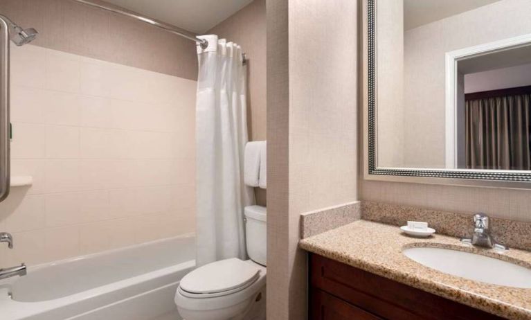 Sonesta ES Suites Tempe guest bathroom, fitted with shower-equipped bath, lavatory, mirror, and sink.