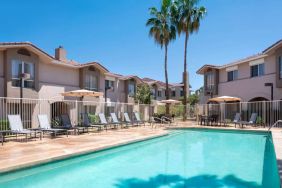 Outdoor pool at Sonesta ES Suites Tempe, featuring shaded tables and chairs, plus sun loungers, by the side.