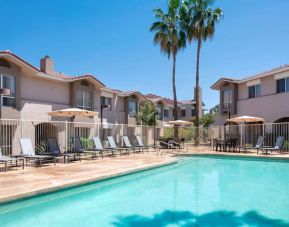 Outdoor pool at Sonesta ES Suites Tempe, featuring shaded tables and chairs, plus sun loungers, by the side.