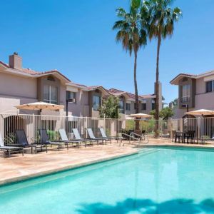 Outdoor pool at Sonesta ES Suites Tempe, featuring shaded tables and chairs, plus sun loungers, by the side.