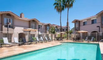 Outdoor pool at Sonesta ES Suites Tempe, featuring shaded tables and chairs, plus sun loungers, by the side.