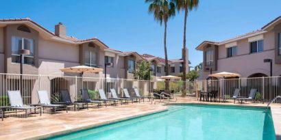 Outdoor pool at Sonesta ES Suites Tempe, featuring shaded tables and chairs, plus sun loungers, by the side.