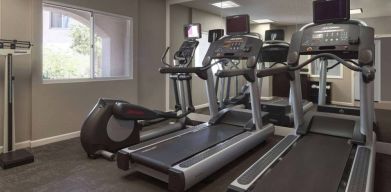 Sonesta ES Suites Tempe’s fitness center has a window, mirrored wall, treadmills, and an elliptical machine.