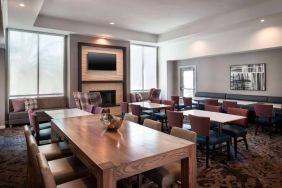 Breakfast area in Sonesta ES Suites Tempe, with mix of table sizes, sofas and chairs, large windows, and a wall-mounted television.