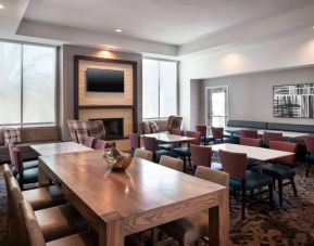 Breakfast area in Sonesta ES Suites Tempe, with mix of table sizes, sofas and chairs, large windows, and a wall-mounted television.