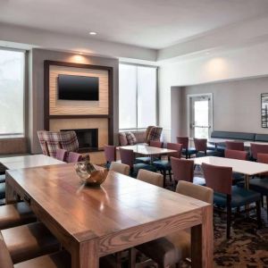 Breakfast area in Sonesta ES Suites Tempe, with mix of table sizes, sofas and chairs, large windows, and a wall-mounted television.