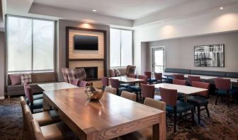 Breakfast area in Sonesta ES Suites Tempe, with mix of table sizes, sofas and chairs, large windows, and a wall-mounted television.