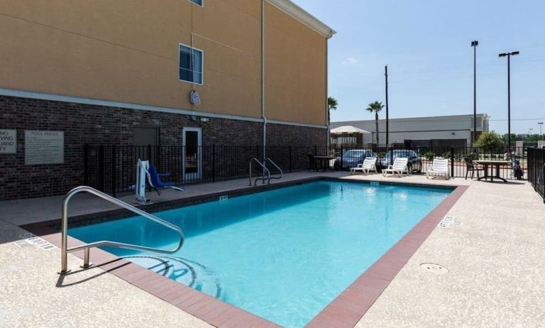 Large outdoor pool with pool chairs at Hotel Pearland.