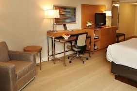 King bed with couch and work space at EnVision Hotel And Conference Center Mansfield Foxboro.