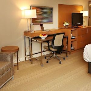 King bed with couch and work space at EnVision Hotel And Conference Center Mansfield Foxboro.