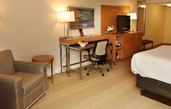 King bed with couch and work space at EnVision Hotel And Conference Center Mansfield Foxboro.