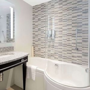 Guest bathroom with shower and bathat Hampton By Hilton London Stansted Airport.