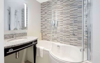 Guest bathroom with shower and bathat Hampton By Hilton London Stansted Airport.