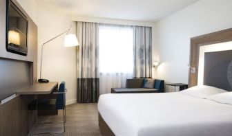 King bed with TV and sofa at Novotel Toronto North York.