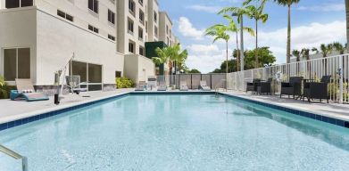 Outdoor pool with chairs at Hampton Inn & Suites Miami Kendall. 