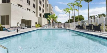 Outdoor pool with chairs at Hampton Inn & Suites Miami Kendall. 