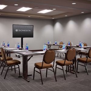 Hotel meeting room, with large table, seating for around 10 attendees, and a large widescreen television.