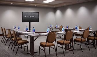 Hotel meeting room, with large table, seating for around 10 attendees, and a large widescreen television.