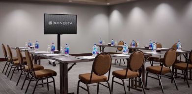 Hotel meeting room, with large table, seating for around 10 attendees, and a large widescreen television.