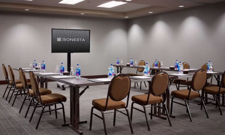 Hotel meeting room, with large table, seating for around 10 attendees, and a large widescreen television.