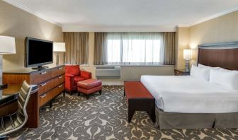 Double bed guest room in Sonesta Los Angeles Airport LAX, featuring armchair, TV, and workspace desk and chair.