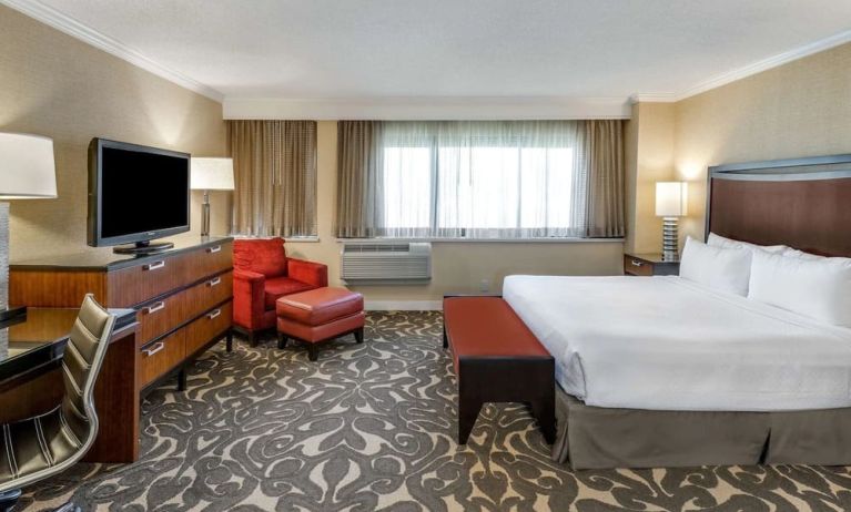 Double bed guest room in Sonesta Los Angeles Airport LAX, featuring armchair, TV, and workspace desk and chair.