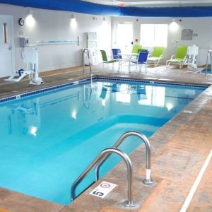 Indoor pool with seating area at Coratel Inn & Suites By Jasper Rochester.