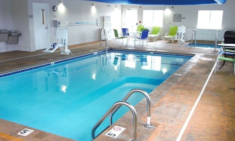 Indoor pool with seating area at Coratel Inn & Suites By Jasper Rochester.