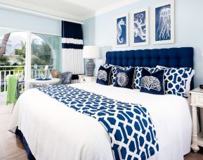 Bright dayroom with white and blue queen size bed and patio view at Oyster Bay Beach Resort. 
