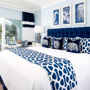 Bright dayroom with white and blue queen size bed and patio view at Oyster Bay Beach Resort. 