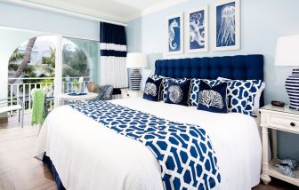 Bright dayroom with white and blue queen size bed and patio view at Oyster Bay Beach Resort. 