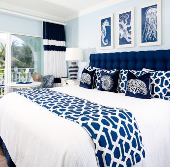 Bright dayroom with white and blue queen size bed and patio view at Oyster Bay Beach Resort. 