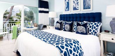 Bright dayroom with white and blue queen size bed and patio view at Oyster Bay Beach Resort. 