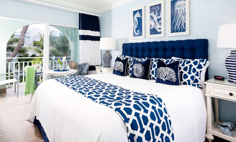 Bright dayroom with white and blue queen size bed and patio view at Oyster Bay Beach Resort. 