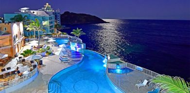 Aerial nighttime angle of lit up Infinity Pool at Oyster Bay Resort in St. Maarten.