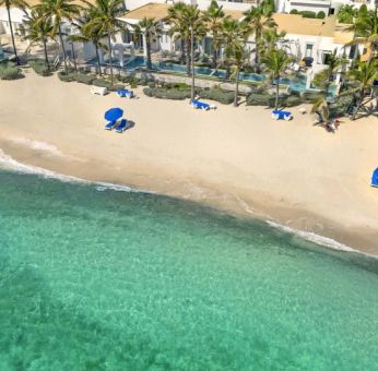 Oyster Bay Resort's beach with sun tanning chairs and waves going on shore. 