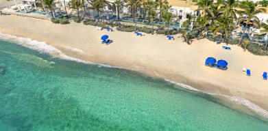 Oyster Bay Resort's beach with sun tanning chairs and waves going on shore. 