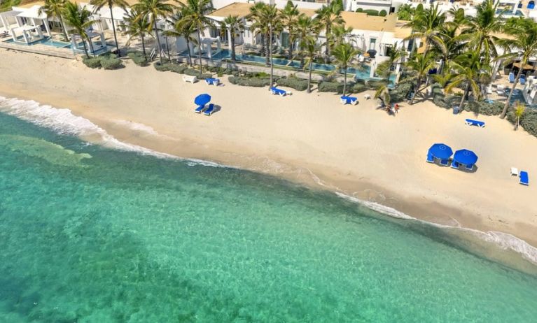 Oyster Bay Resort's beach with sun tanning chairs and waves going on shore. 