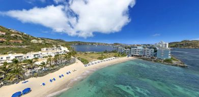 Oyster Bay Resort in St. Martin with beach chairs lined along beach. 