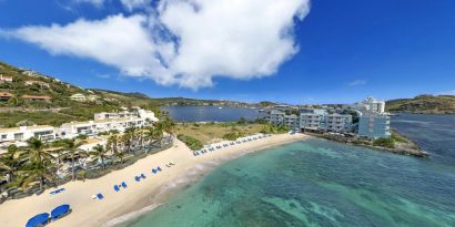 Oyster Bay Resort in St. Martin with beach chairs lined along beach. 