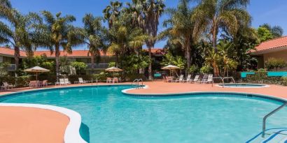 Outdoor pool with palm trees at Uptown Oasis San Jose Airport.